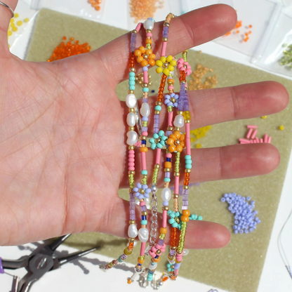 Hand holding colorful beaded bracelets with a crafting background