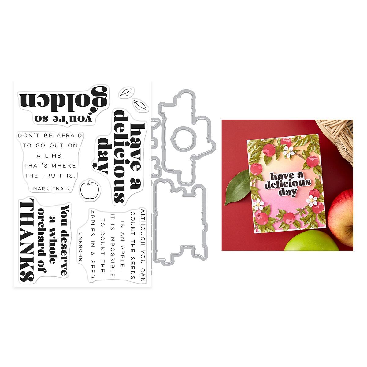 Metal die cutters with printed phrases and a card with apples and flowers on a red background.