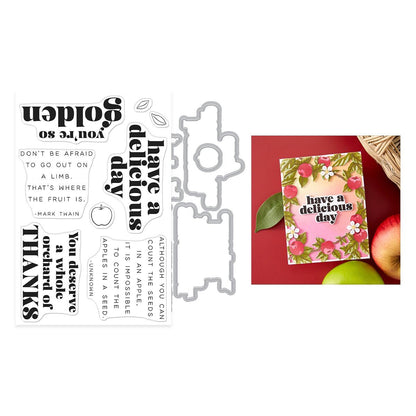 Metal die cutters with printed phrases and a card with apples and flowers on a red background.