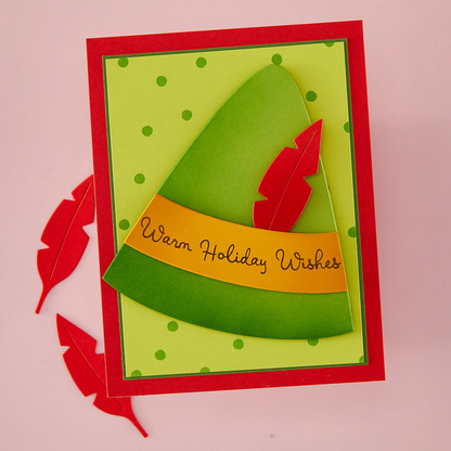 Holiday card with green tree design and red feathers on a pink background using Hero Arts Die