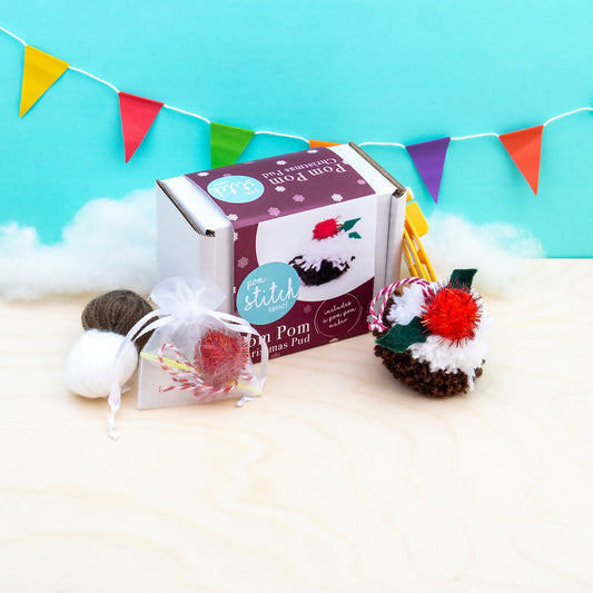 Pom pom craft kit with materials on a light blue background with colorful flags.