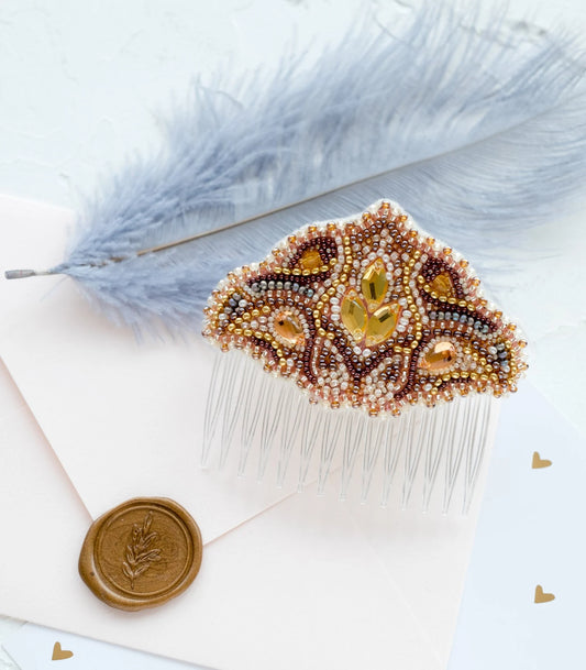Decorative hair comb with beads on a white surface with dried flowers and an envelope.