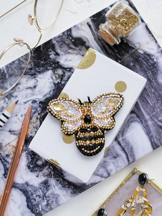 Decorative brooch with bee design on a marble surface