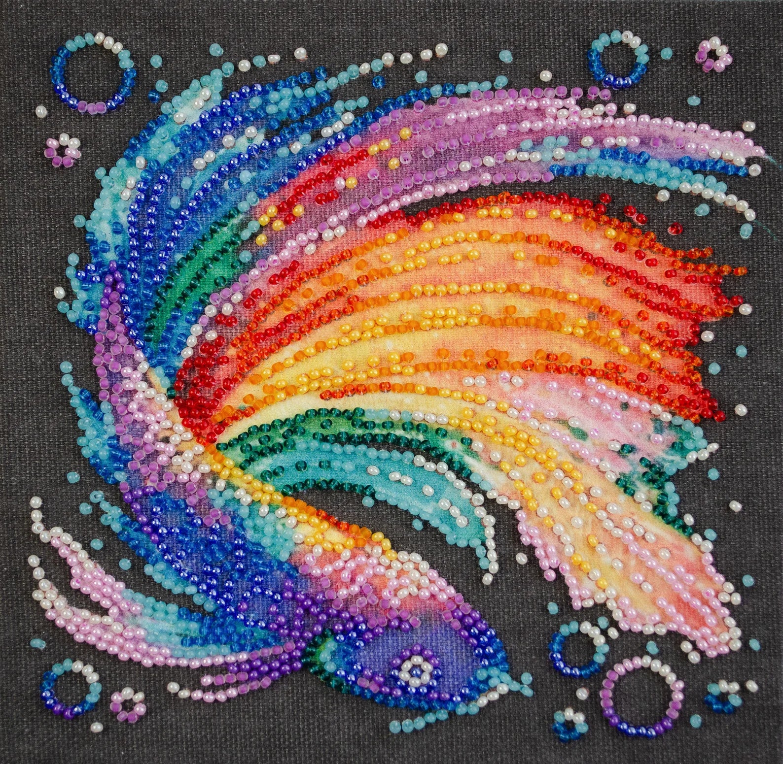 Colorful beaded design of a rainbow on a black background