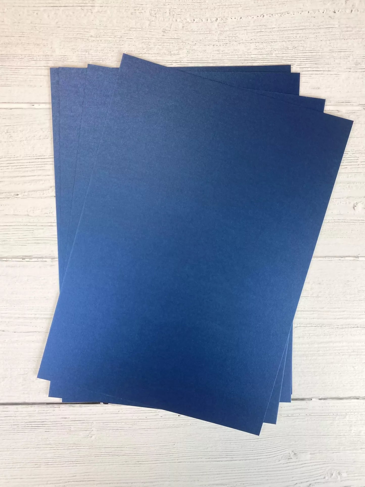 Three blue sheets of paper on a light wooden surface