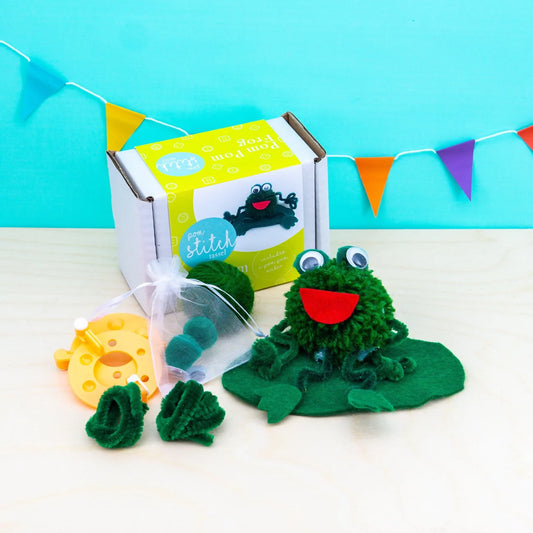 Frog craft kit with materials and a box labeled 'Stitch' on a light blue background.