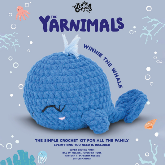 Crocheted blue whale toy with 'The Yarnimals' branding on a light blue background.
