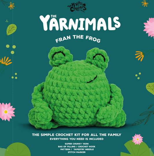 Crocheted frog toy with 'The Yarnimals' branding on a green background with floral and leaf patterns.