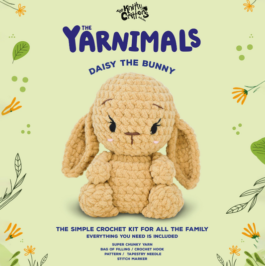 Crocheted bunny toy with 'The Yarnimals' branding on a light green background with floral patterns.